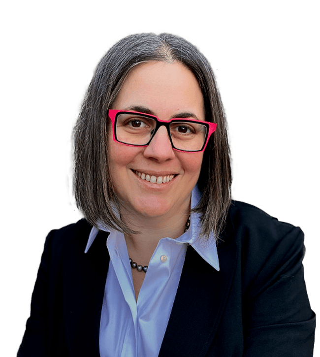 Smiling woman with shoulder-length gray hair, pink-framed glasses, wearing a light blue collared shirt and dark blazer.